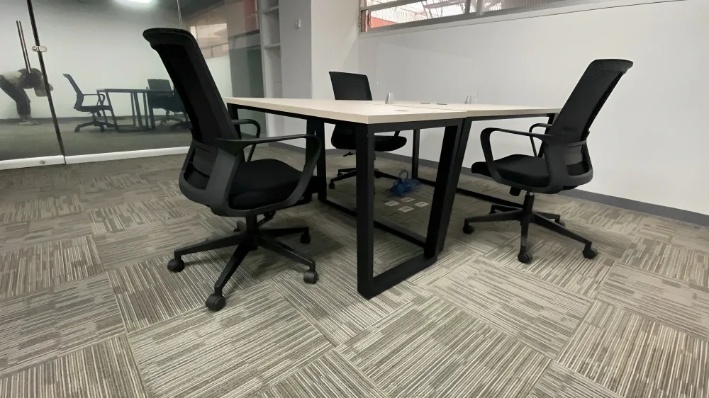 Mesa de juntas para cuatro con estructura metálica negra y sillas operativas de malla