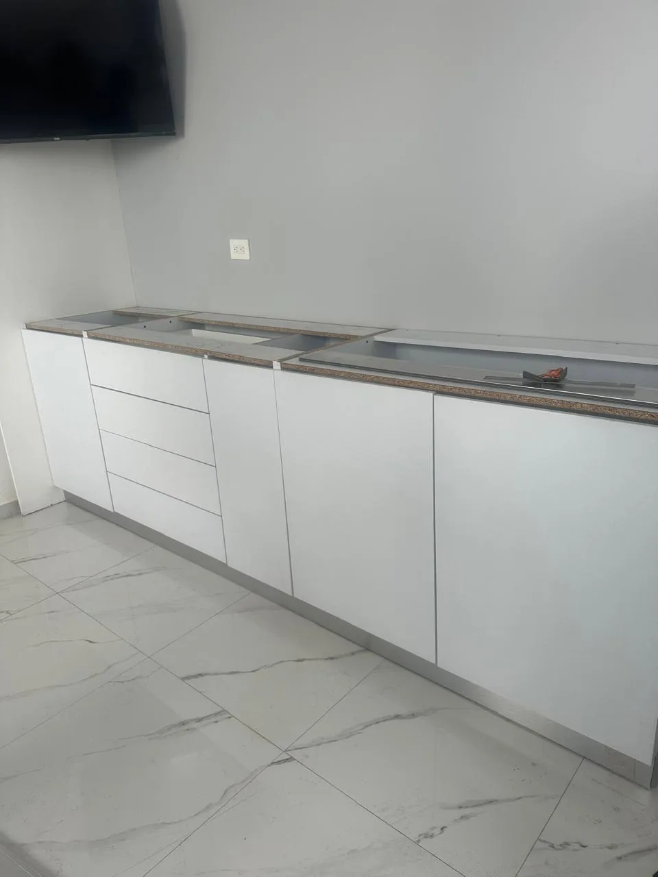 Mueble bajo largo con cajones y puertas blancas a lo largo del muro