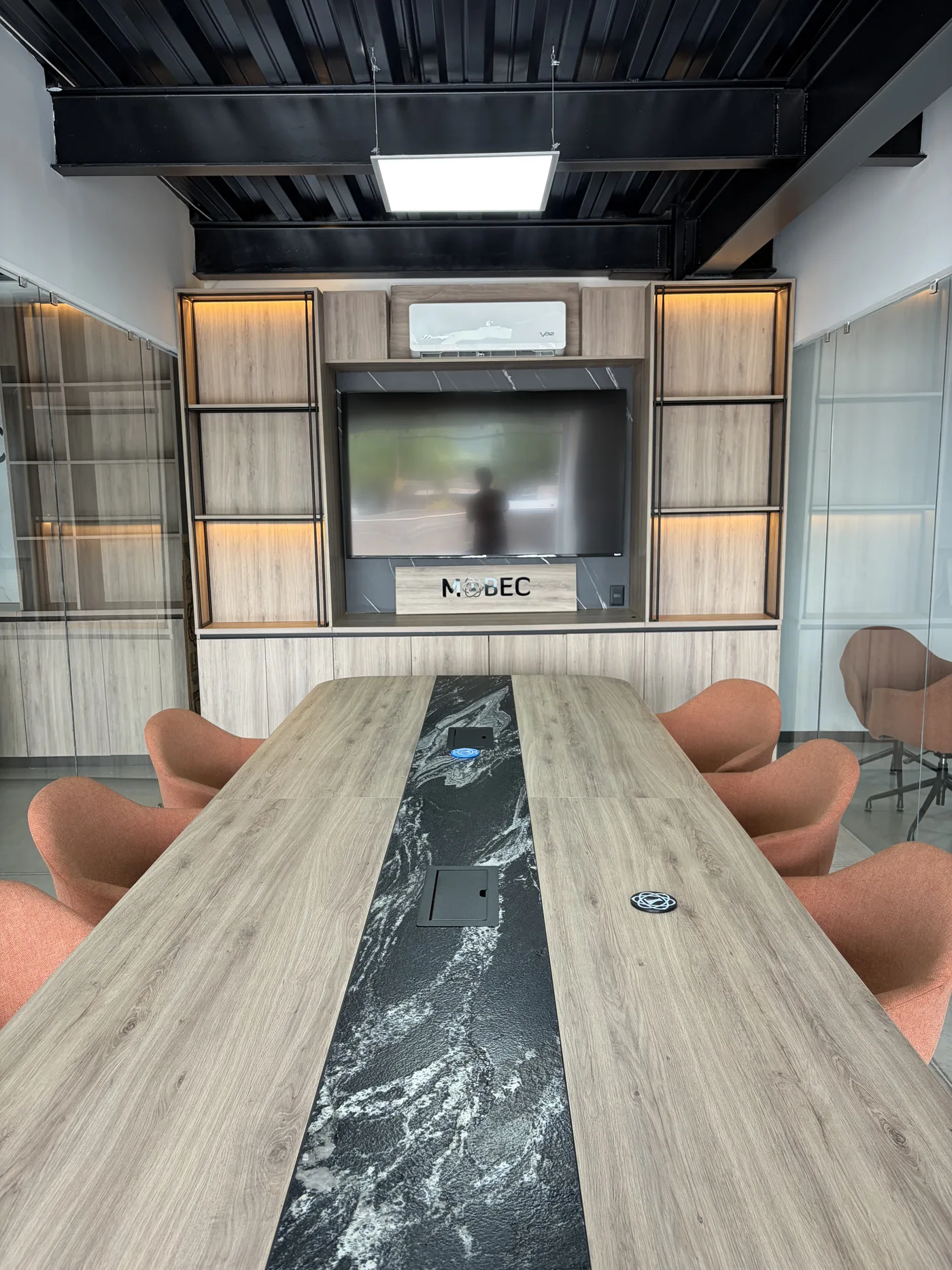 Sala de juntas con mesa larga de cubierta de mármol negro y sillas color terracota