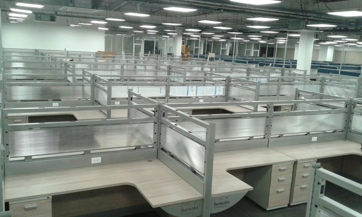 Hileras de estaciones de trabajo con mamparas de cristal en un piso corporativo
